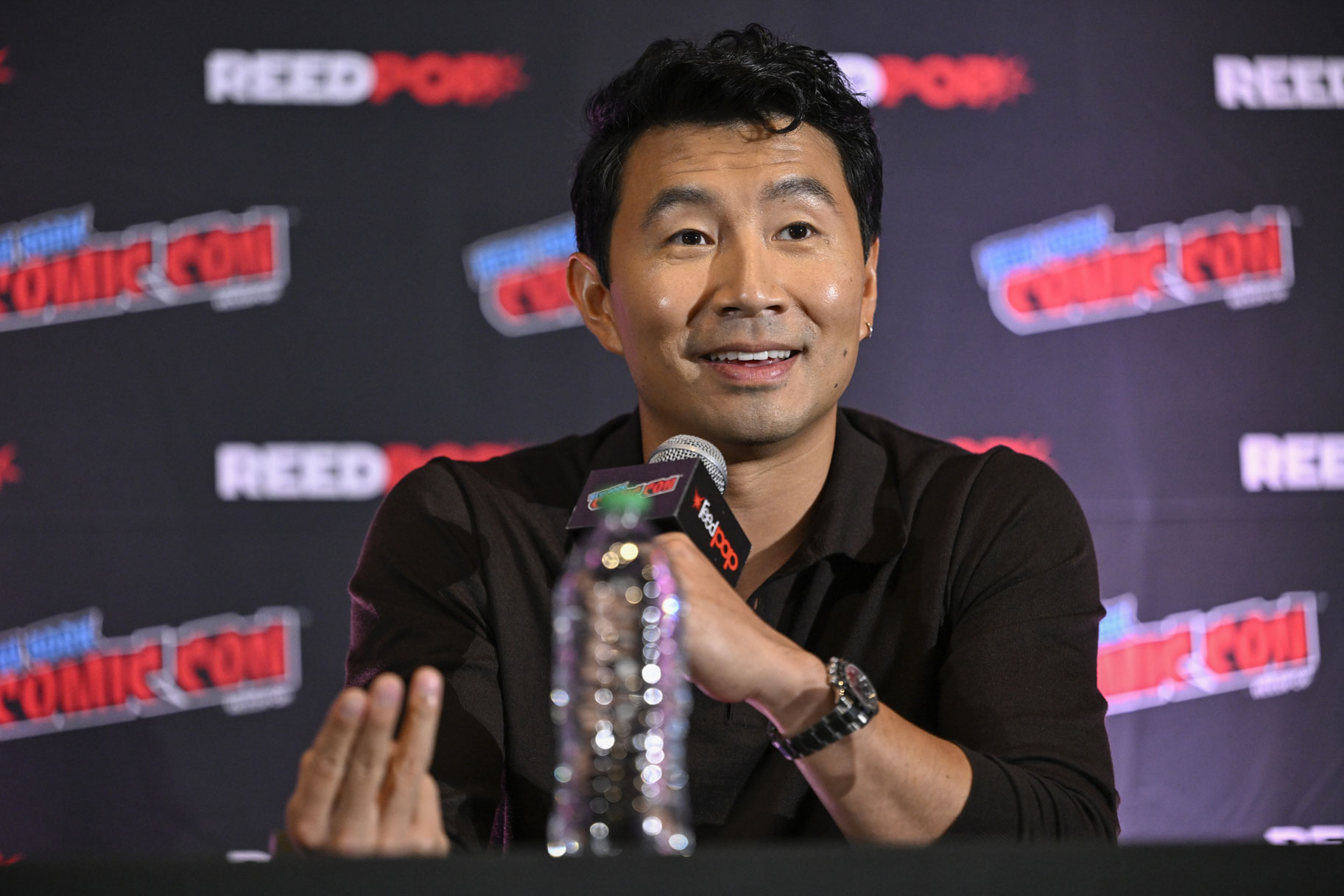 Simu Liu talking into a microphone at New York Comic Con.