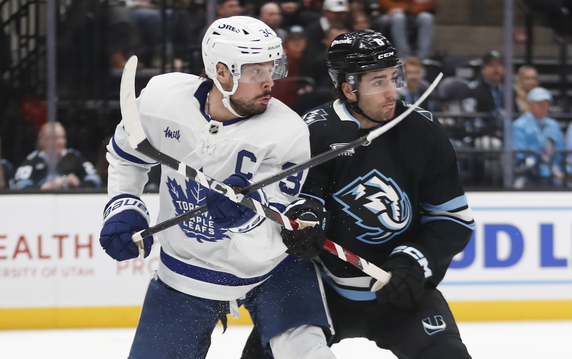 Auston Matthews #34 of the Toronto Maple Leafs battles for position in front of the net with John Marino #8 of the Utah Mammoth.