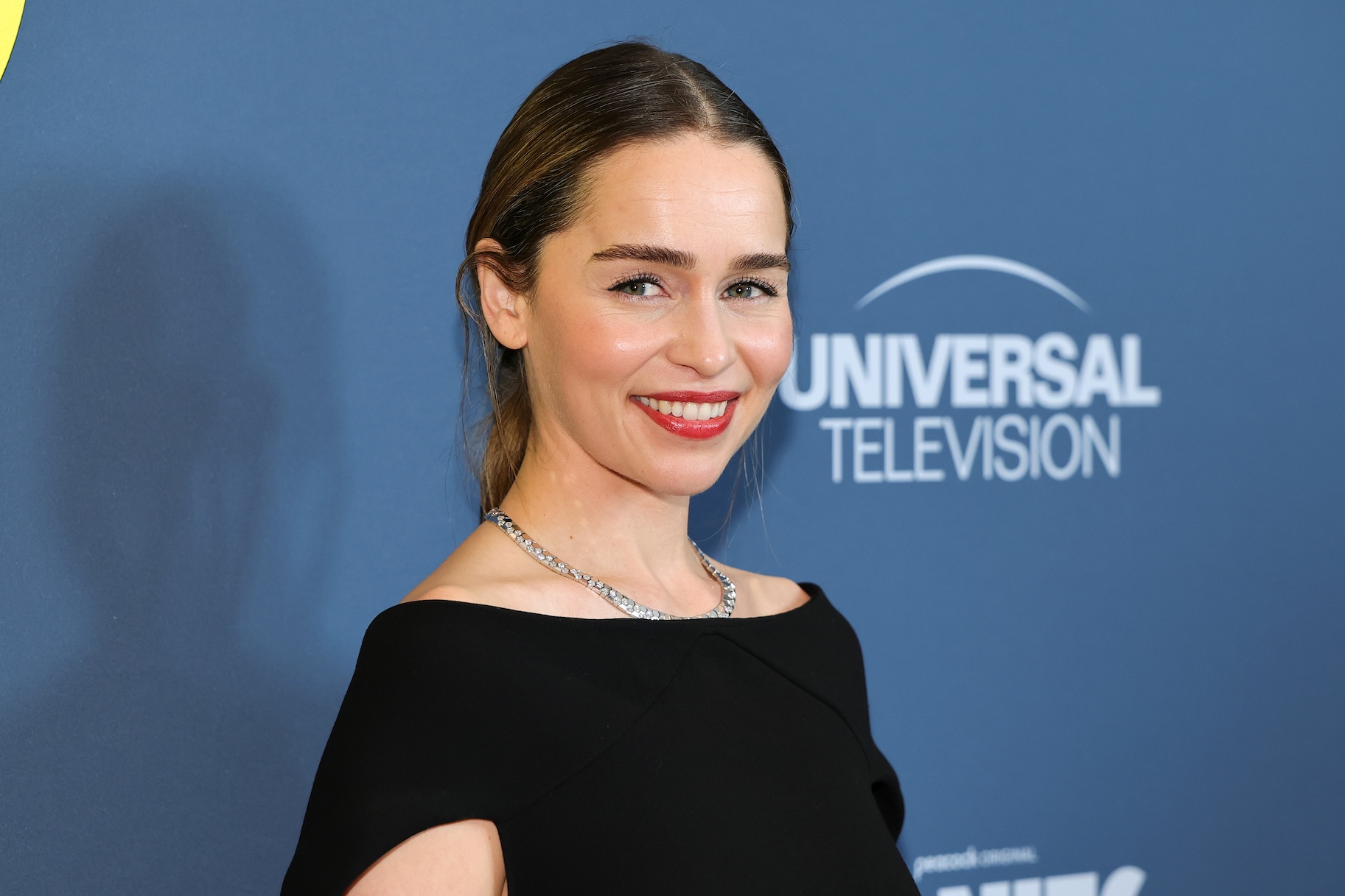 Emilia Clarke smiles in a black top.