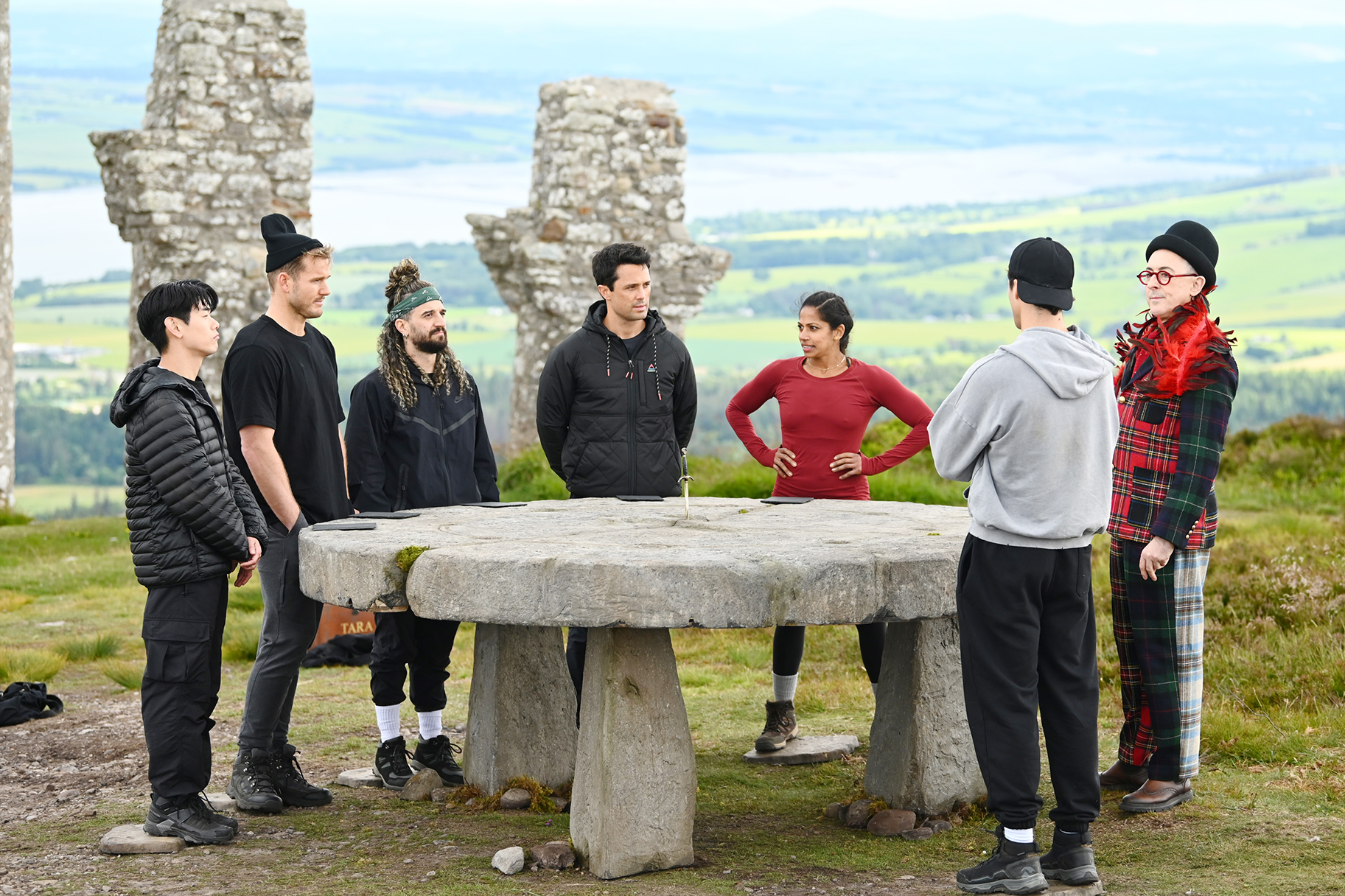 Eric Nam, Colton Underwood, Mark Ballas, Stephen Colletti, Natalie Anderson, Rob Rausch, and Alan Cumming talking in The Traitors Season 4 Episode 7.