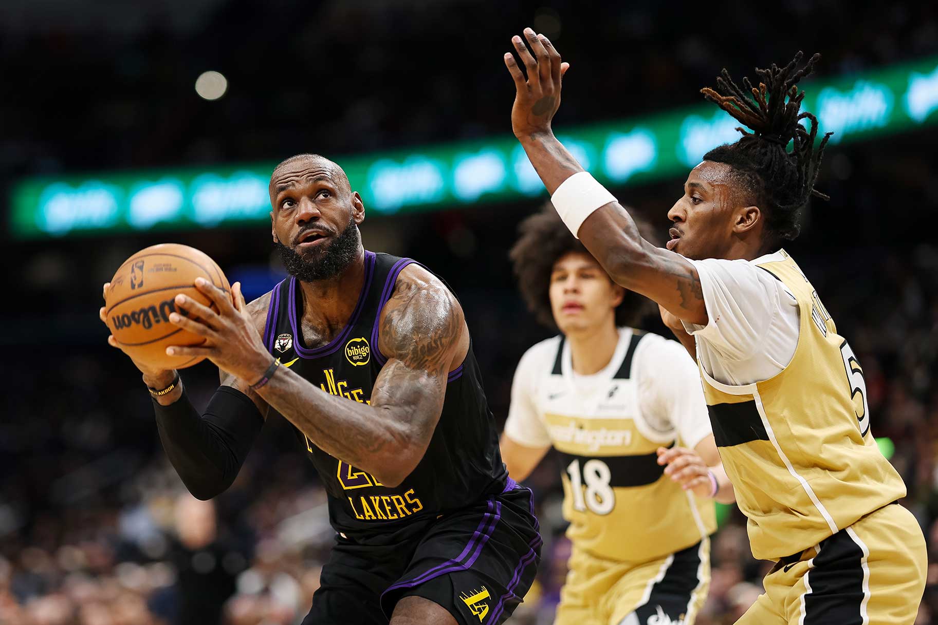 LeBron James of the Los Angeles Lakers looking to shoot the ball past two Washington Wizards players.