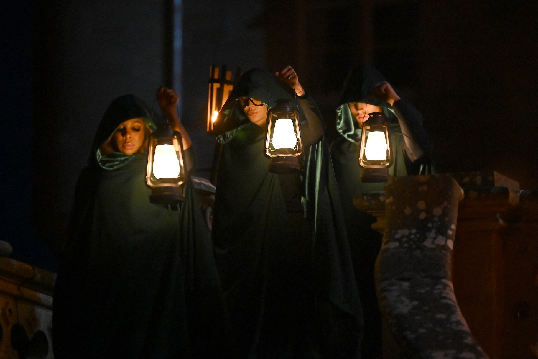 Candiace Dillard Bassett, Lisa Rinna, and Rob Rausch stand in hoods while holding lanterns on The Traitors Episode 401.