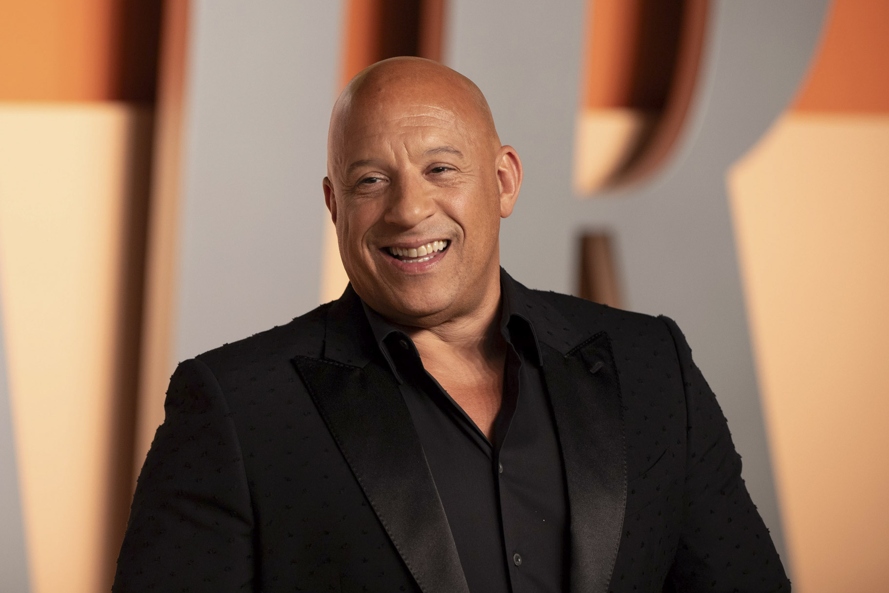 Vin Diesel smiling in front of a step and repeat.