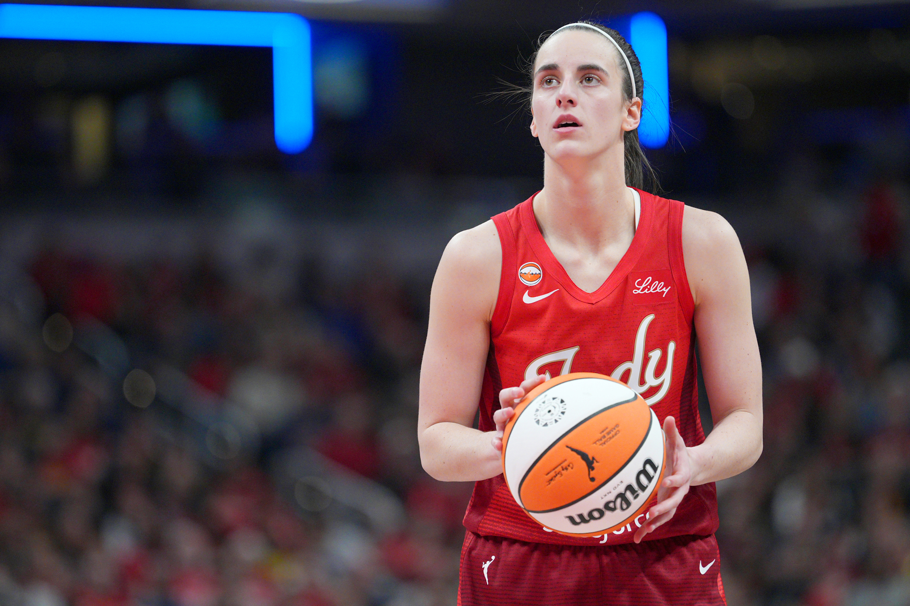 Caitlin Clark holidng a basketball while on the basketball court.