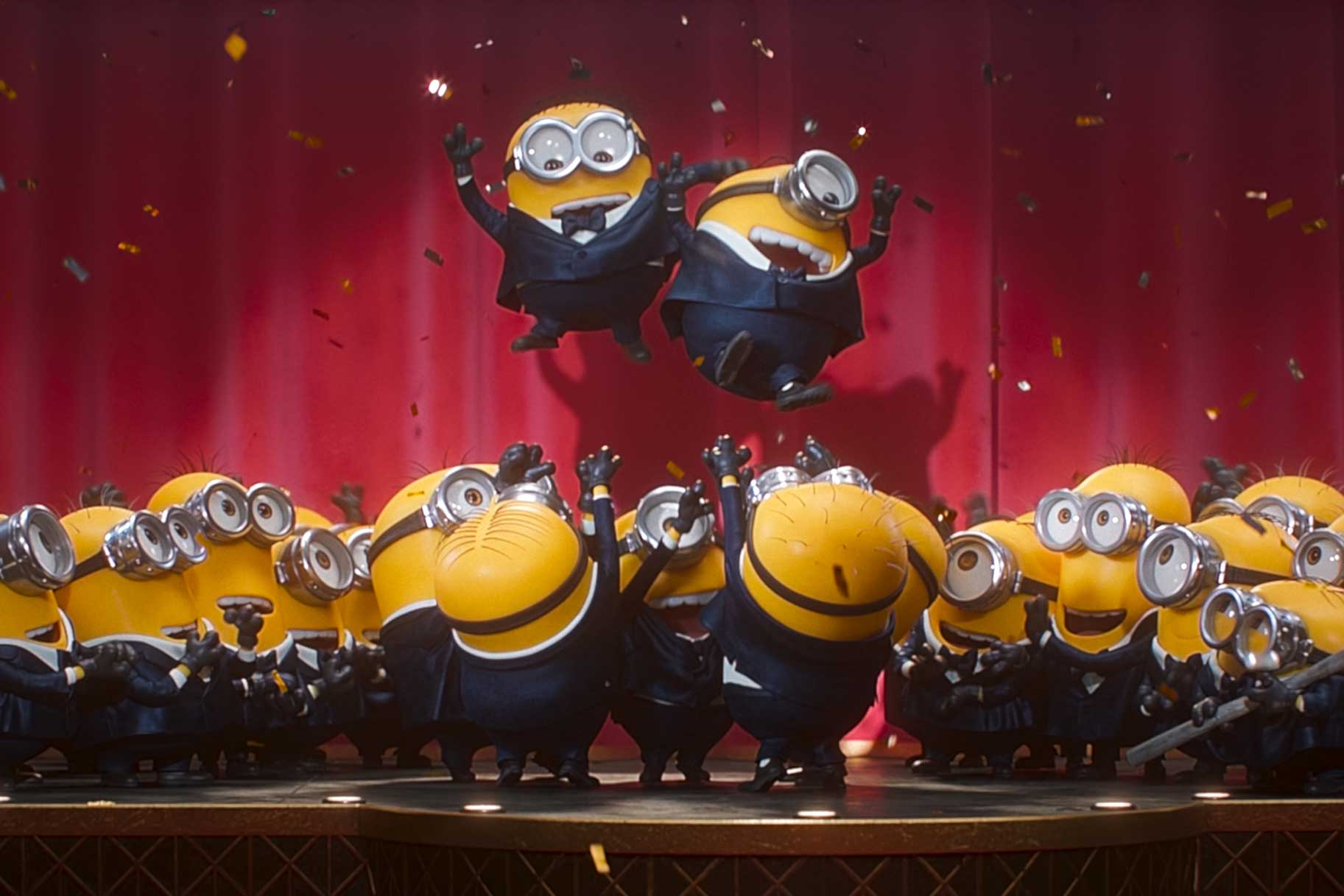 Minions performing on stage and climbing on each other in Minions & Monsters (2026).