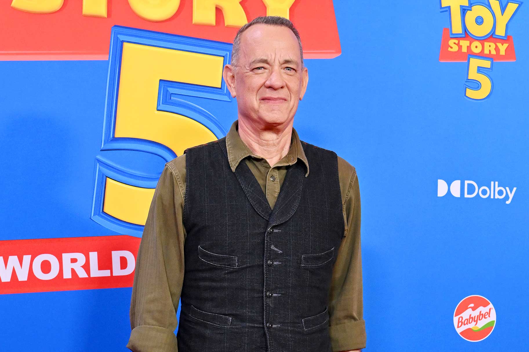 Tom Hanks smiling and posing at the premiere of Toy Story 5.
