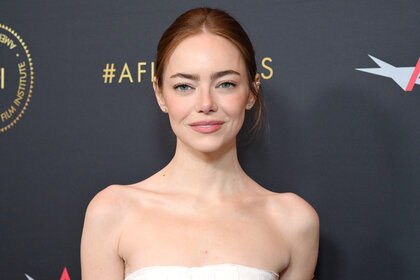 Emma Stone smiling in a white dress at the AFI Awards.