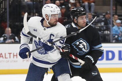 Auston Matthews #34 of the Toronto Maple Leafs battles for position in front of the net with John Marino #8 of the Utah Mammoth.