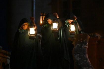 Candiace Dillard Bassett, Lisa Rinna, and Rob Rausch stand in hoods while holding lanterns on The Traitors Episode 401.