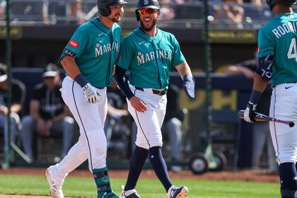 Cal Raleigh and Miles Mastrobuoni of the Seattle Mariners on a baseball feild.