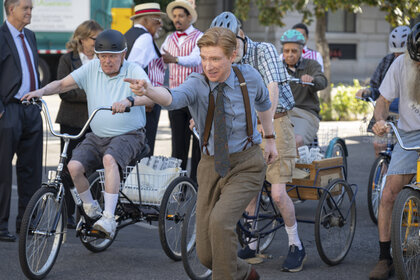 Ned (Domhnall Gleeson) pointing while surrounded by cyclists in The Paper Season 2 Episode 6.