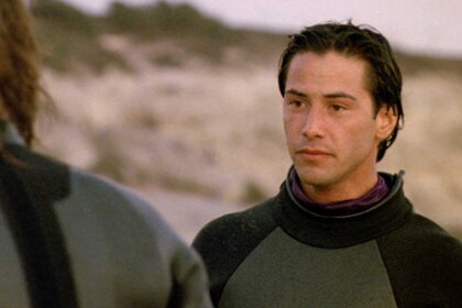 Johnny Utah talking to another person on the beach in Point Break (1991).