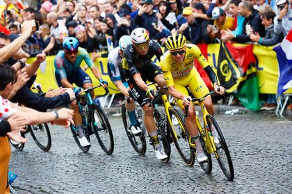 A group of bikers going up a stone street with a crowd a people cheering during the 112th Tour de France.