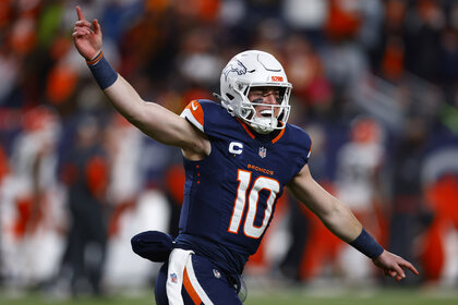 Bo Nix, #10 of the Denver Broncos, celebrating during a game wearing a midnight blue jersey.