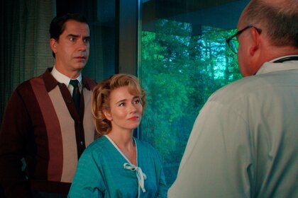 Hamish Linklater as Elias and Linda Cardellini as Pam Voorhees stand facing Jeffery Bean as Dr. Valentine in a room with large windows.