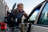 Director Curry Barker next to a camera looking into a car window on the set of Obsession (2026)