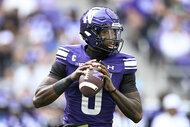 Aidan Chiles of the Northwestern Wildcats holds a football and looks downfield during a game against the Ball State Cardinals.