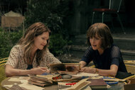 Meghann Fahy as Charlie and Rose Byrne as Sam looking at photos and old books on The Good Daughter Season 1.
