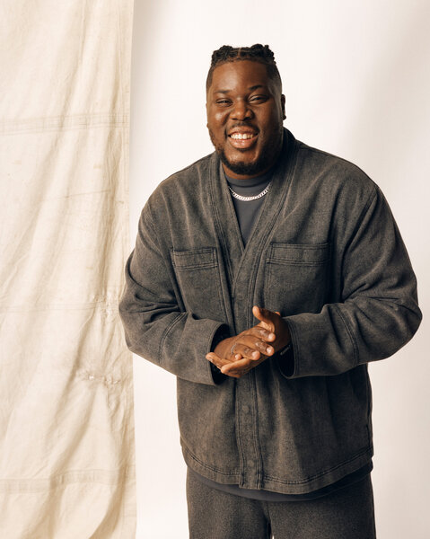 Hammed Animashaun posing in front of a cream backdrop.