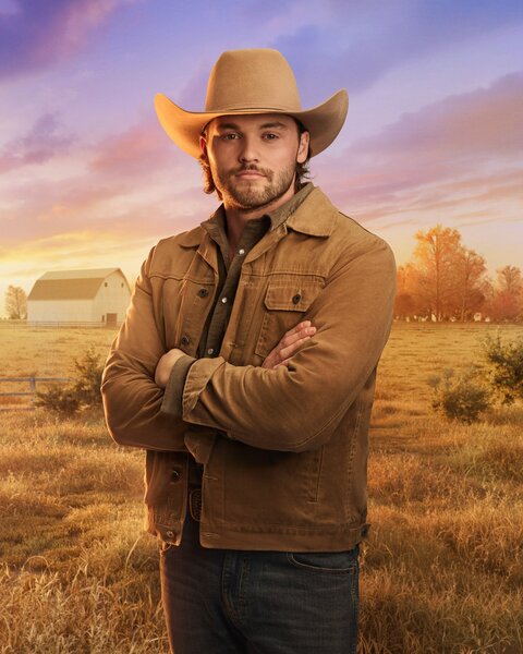 Jesse McBee standing in front of a farm field, trees, and dusk skies.