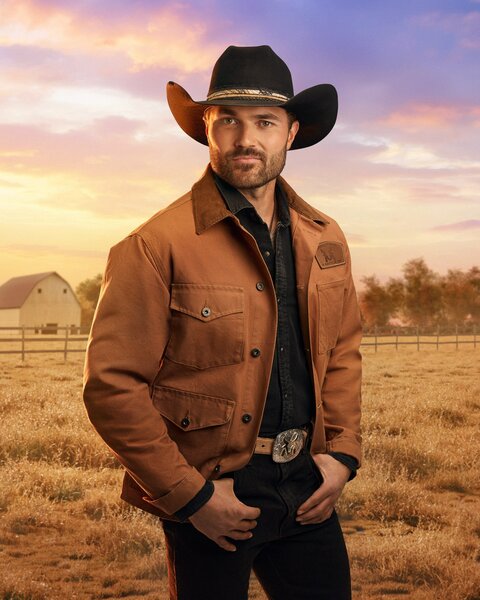 Steven McBee Jr. standing in front of a farm field, trees, and dusk skies.