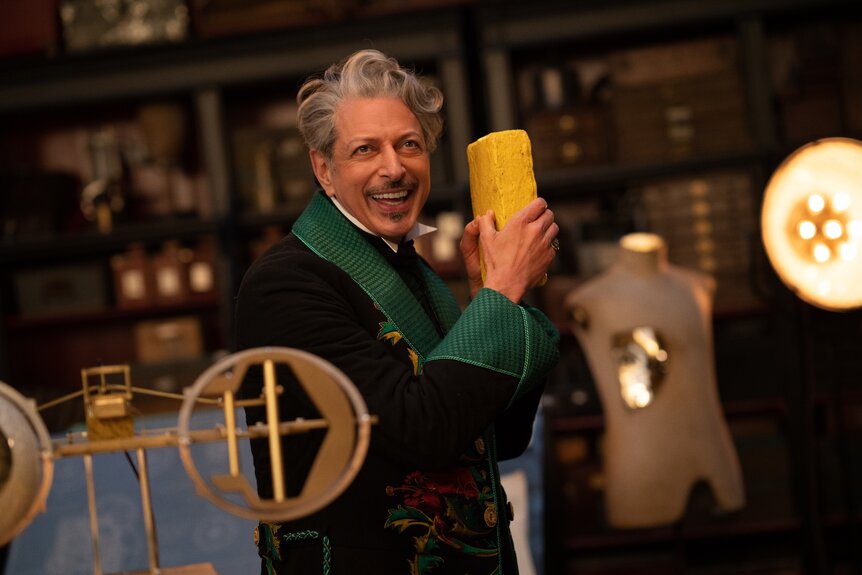 The Wizard of Oz (Jeff Goldblum) smiles while holding a yellow brick in Wicked For Good (2025).