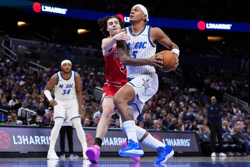Paolo Banchero #5 of the Orlando Magic draws a foul from Josh Giddey #3 of the Chicago Bulls during a game.
