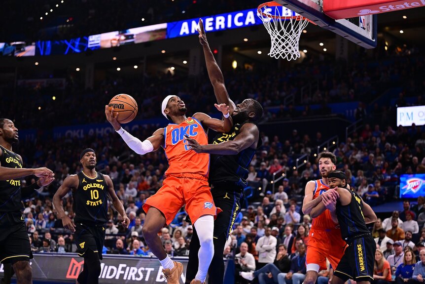 Shai Gilgeous-Alexander #2 of the Oklahoma City Thunder attempts a shot in front of Draymond Green #23 of the Golden State Warriors/