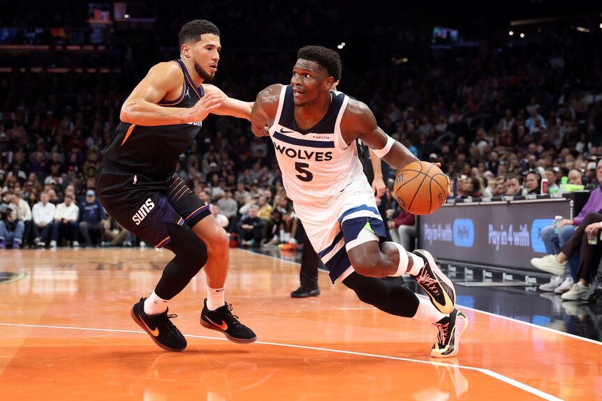 Anthony Edwards of the Minnesota Timberwolves drives to the basket against Devin Booker #1 of the Phoenix Suns.