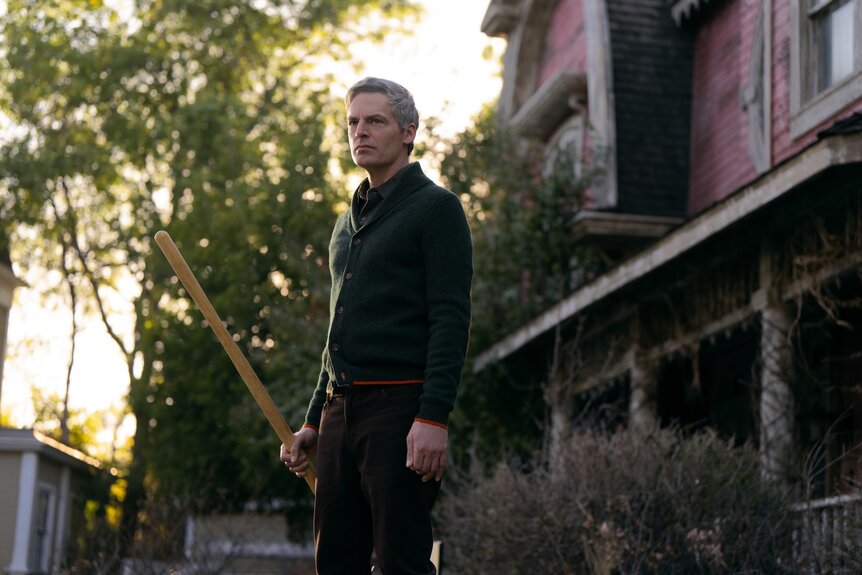 Gary (Justin Kirk) frowns while holding a stick on The 'Burbs Season 1.