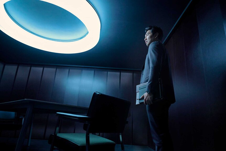 Alexander in a dimly lit room with a giant light in The Copenhagen Test Season 1 Episode 1.
