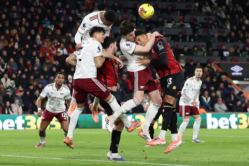 Declan Rice of Arsenal heads clear under pressure from AFC Bournemouth's James Hill during a Premier League match.