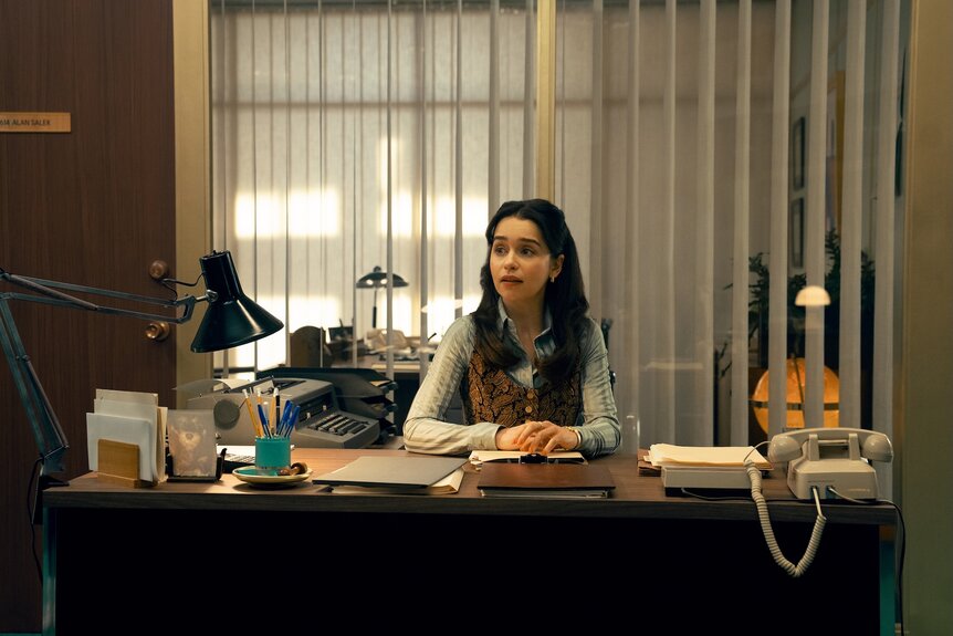 Bea (Emilia Clarke) works at a desk on Ponies Episode 103.