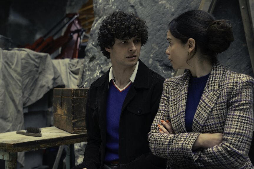 Sasha (Petro Ninovskyi) and Bea (Emilia Clarke) stand close to each other on Ponies Episode 106.