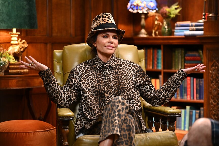 Lisa Rinna shrugs in a full cheetah print suit and fedora on The Traitors Episode 401.