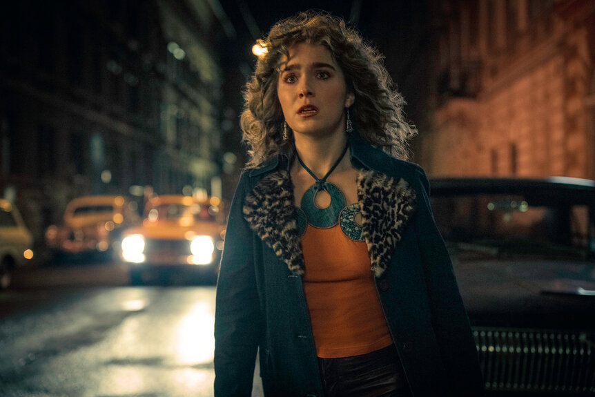 Twila outside at night next to cars in PONIES Season 1 Episode 3.