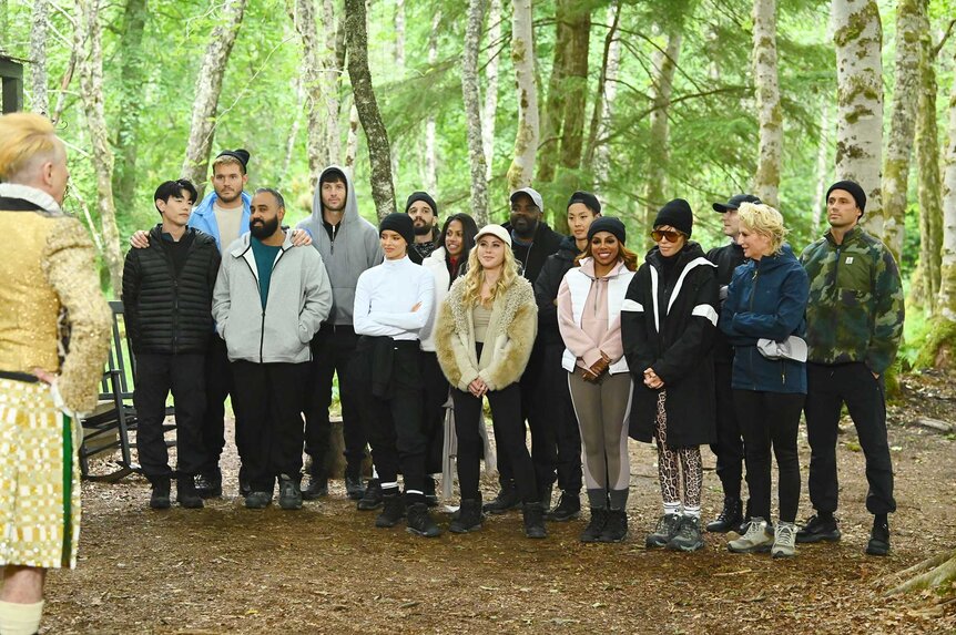 Eric Nam, Colton Underwood, Yam Yam Arocho, Rob Rausch, Maura Higgins, Mark Ballas, Natalie Anderson, Tara Lipinski, Ron Funches, Kristen Kish, Candiace Dillard Bassett, Lisa Rina, Johnny Weir, Dorinda Medley, and Stephen Colletti standing together outside on The Traitors Season 4 Episode 6.