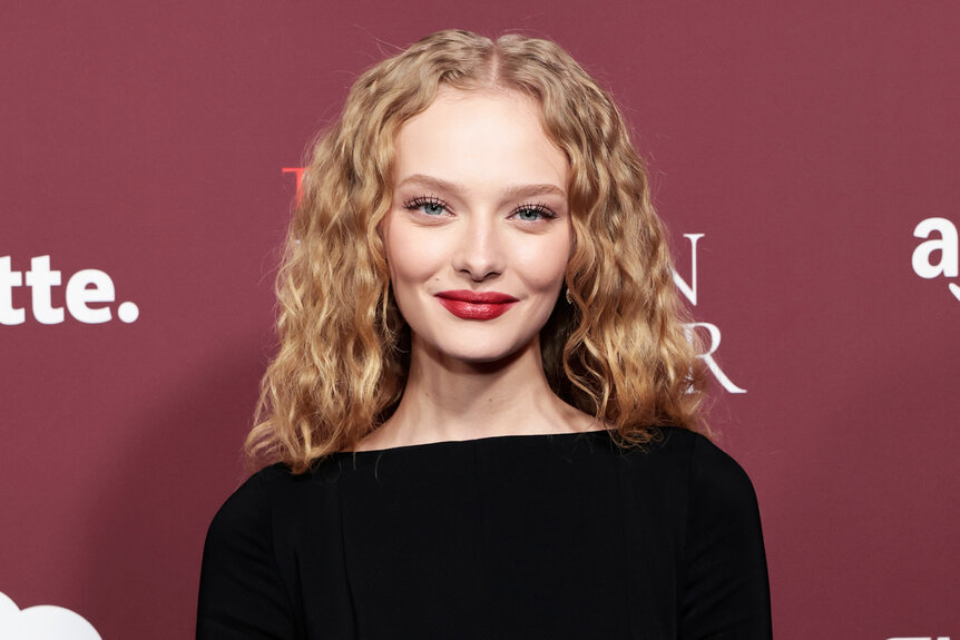 Amiah Miller smiles in a black dress.