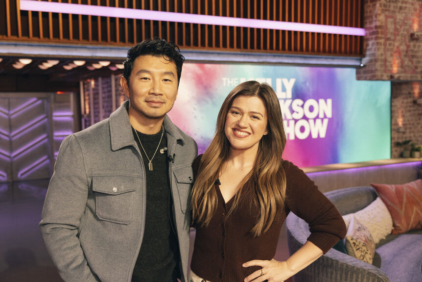 Simu Liu smiles with Kelly Clarkson at The Kelly Clarkson Show Season 7 Episode 74.