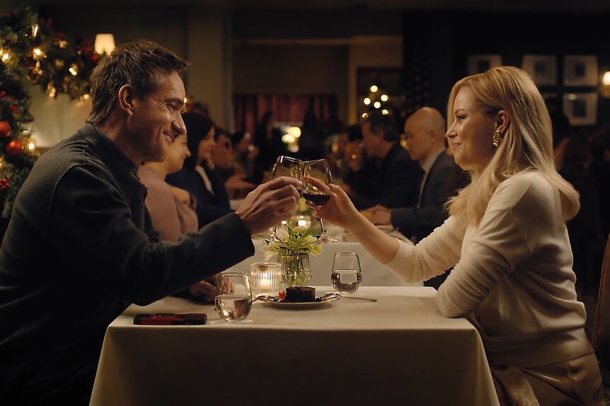 Les (Matthew Macfadyen) and Lindy (Elizabeth Banks) cheers wine glasses at a restaurant on The Miniature Wife Season 1.