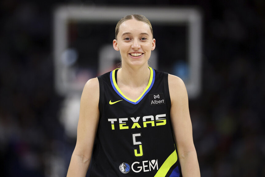 Paige Bueckers, #5 of the Dallas Wings, smiles on the basketball court during a game.