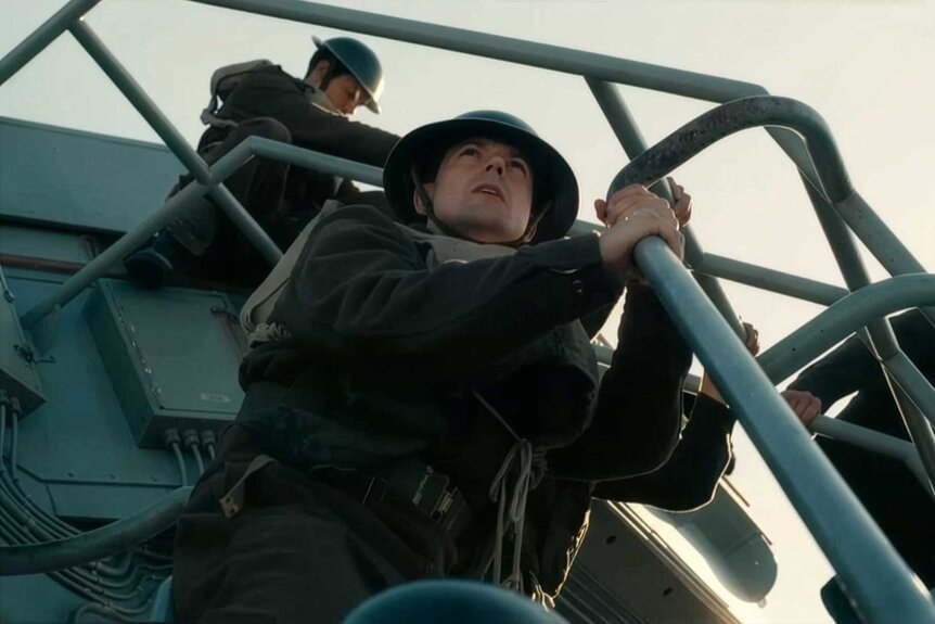 Men hanging off the edge of a boat during the trailer in Dunkirk (2017).