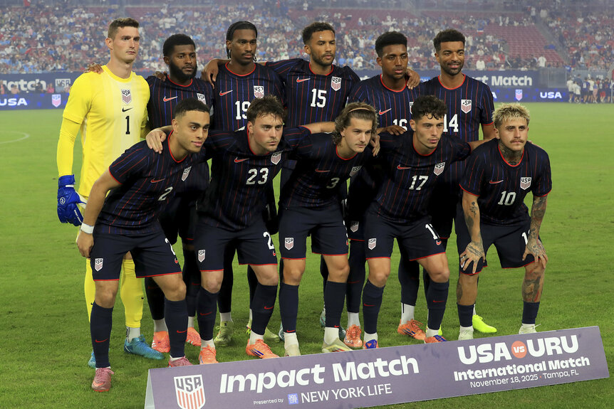 The US Mens National Soccer Team posing on a field ahead of a match.