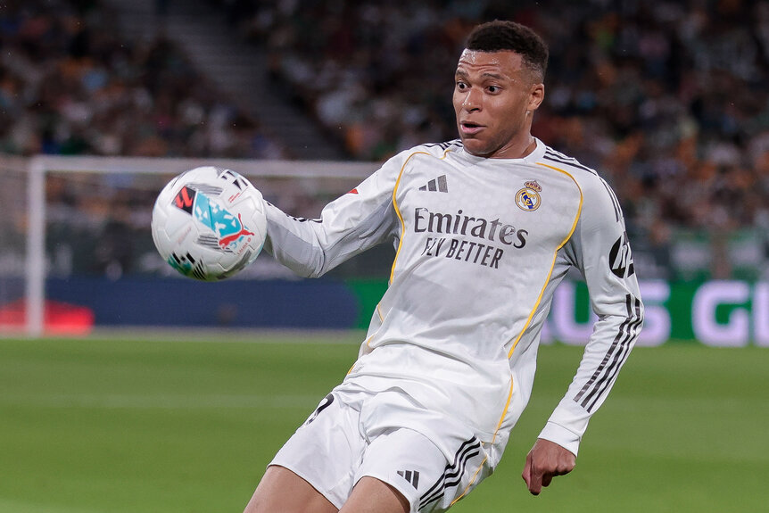 Kylian Mbappe playing on a soccer field ready to kick a ball.