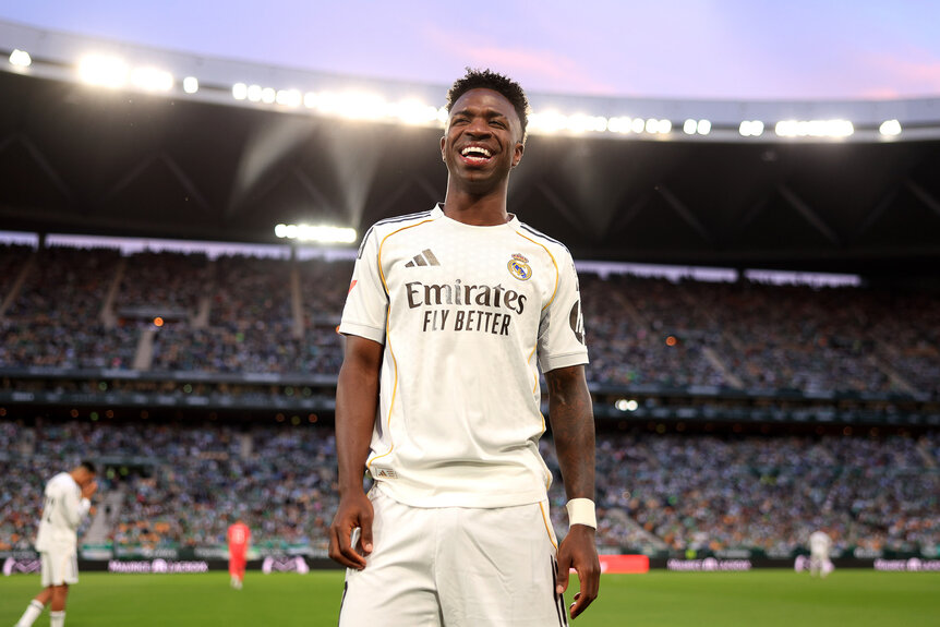 Vinicius Junior standing on the field in a soccer stadium.
