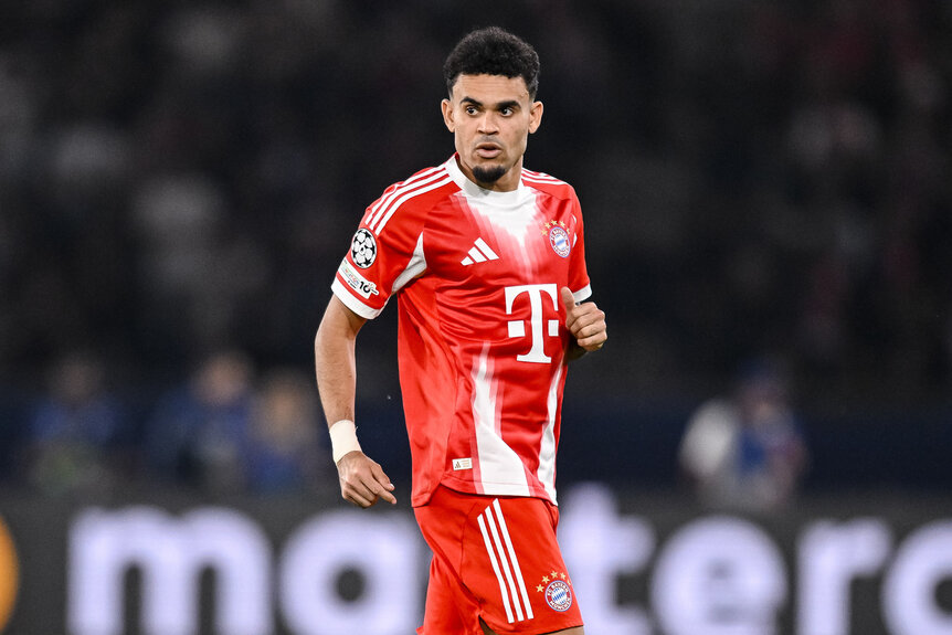 Luis Díaz wearing a red soccer uniform on a soccer field.