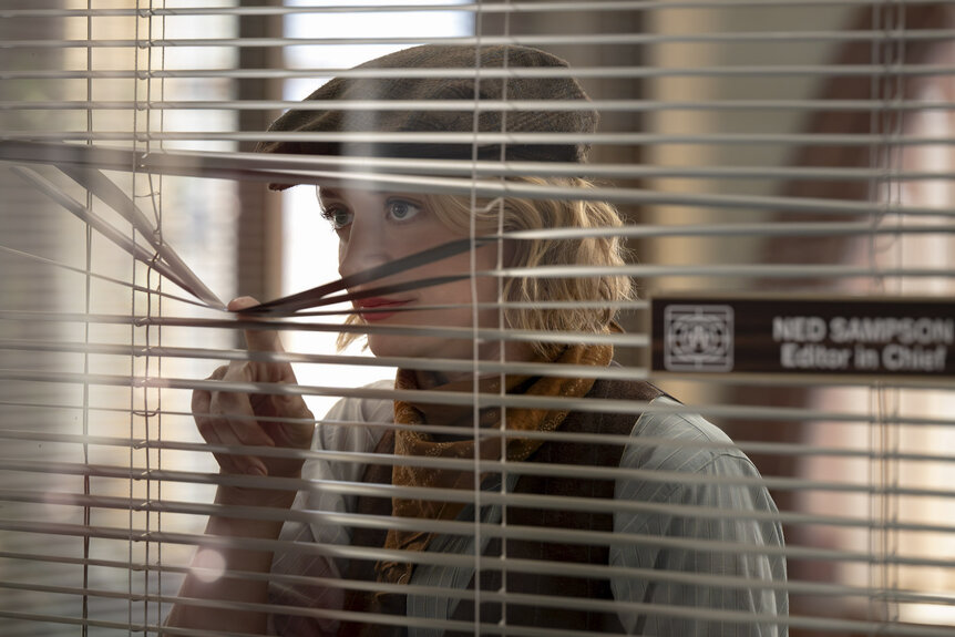 Mare (Chelsea Frei) looking through blinds in The Paper Season 2 Episode 6.