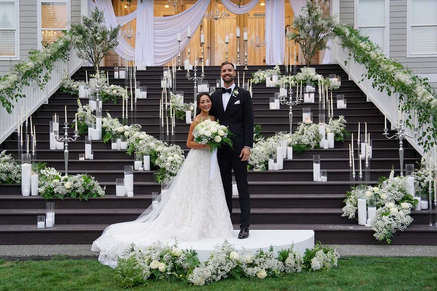 Michelle Le and Cameron Mitchell posing outside in front of wedding decor on Married at First Sight Season 20 Episode 2.