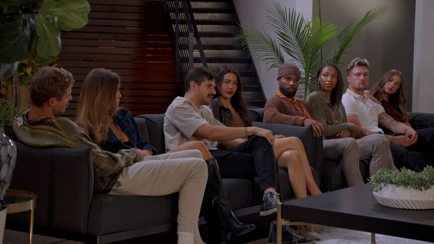 Adam Dehmlow, Marissa Mey, Felipe Cruz, Tori Dahl, Mecca Amen, BelleJolie Force, Devin Short, and Caitlin Grimm sitting on a couch together in Married at First Sight Season 20 Episode 9.