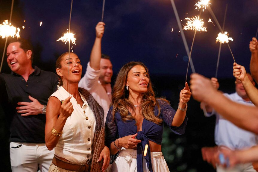 Paul Connell, Elizabeth McGraw, and Dolores Catania holding sparklers in The Real Housewives of Rhode Island Season 1.
